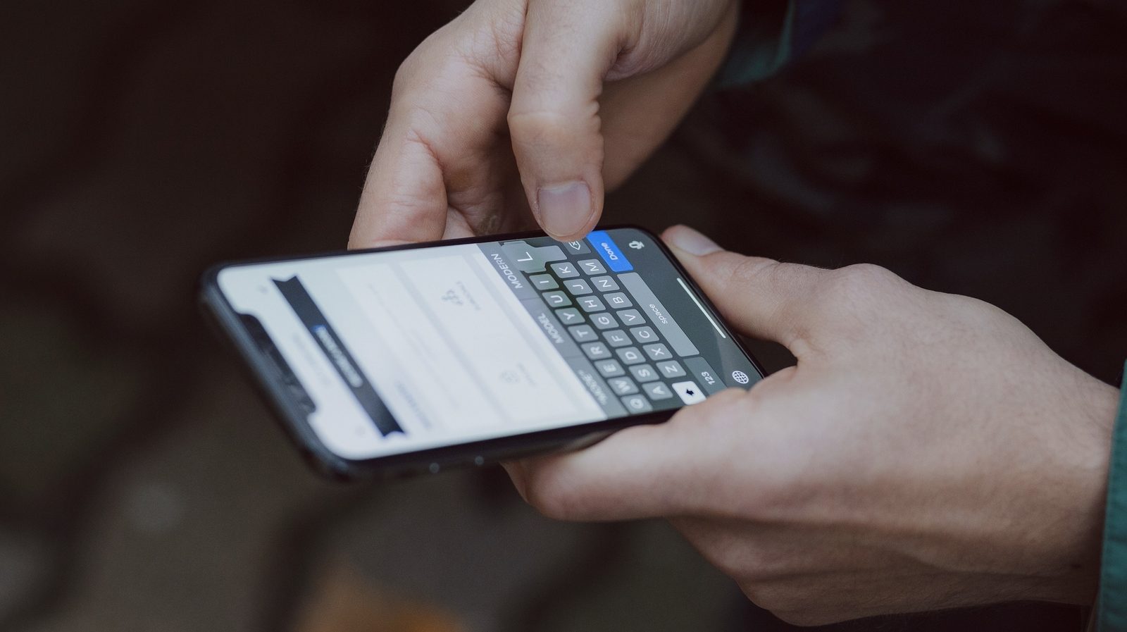 Hands typing a post on a mobile phone.