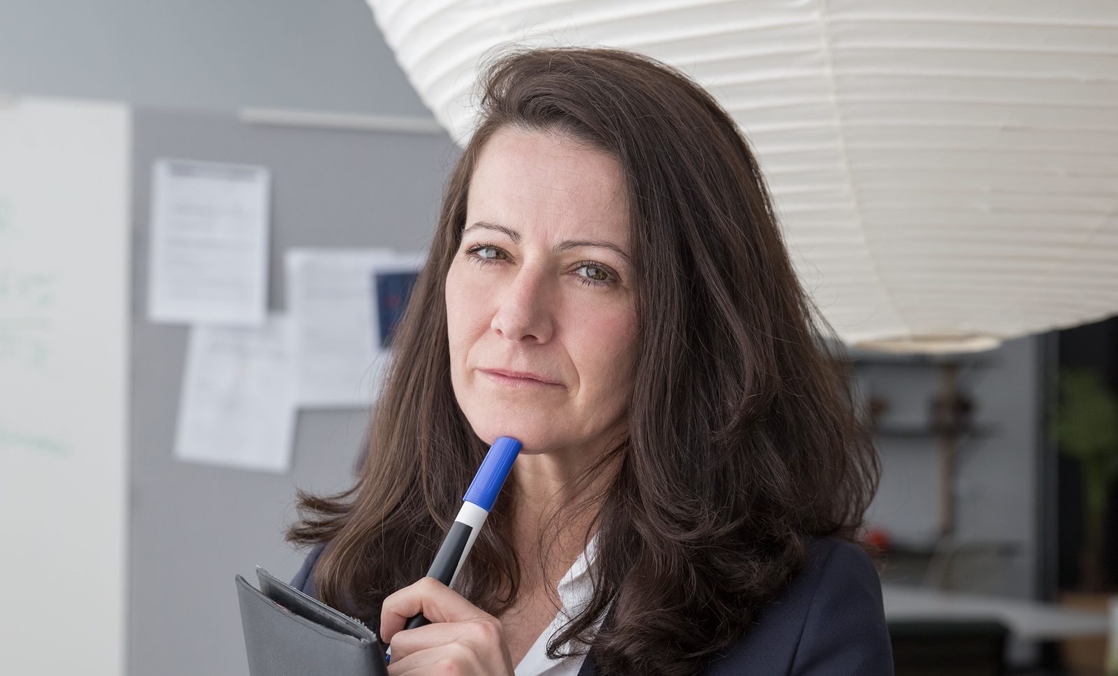 Woman thinking with a pen against her chin.