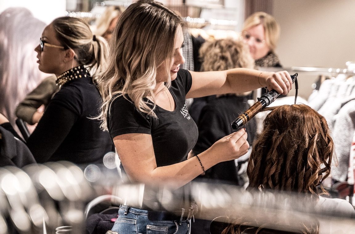 Hairdresser curling a client’s hair with a curling iron.